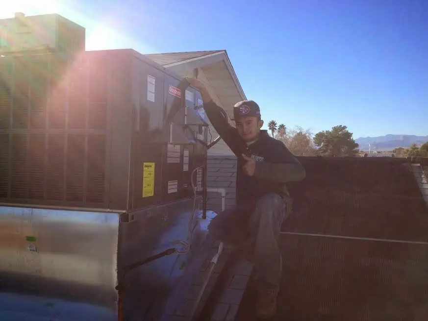 HVAC technician performing Air Duct Cleaning on a rooftop unit in Maine